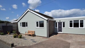 A single-story building with a sloped roof, a front porch, and a small garden area with a bench. - 4 Bed in Chathill (oc-82235) (Beadnell)