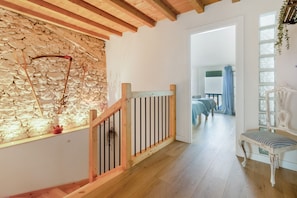 A wooden staircase leading to a room with a stone wall, a bed, and a view of the outdoors. - Holiday Home 'Verde & Mar' with Sea Views, Private Garden and Wi-Fi (Islares)
