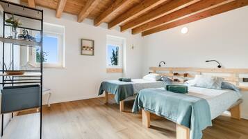 Een kamer met twee bedden, houten vloeren, een plank met planten en een raam.