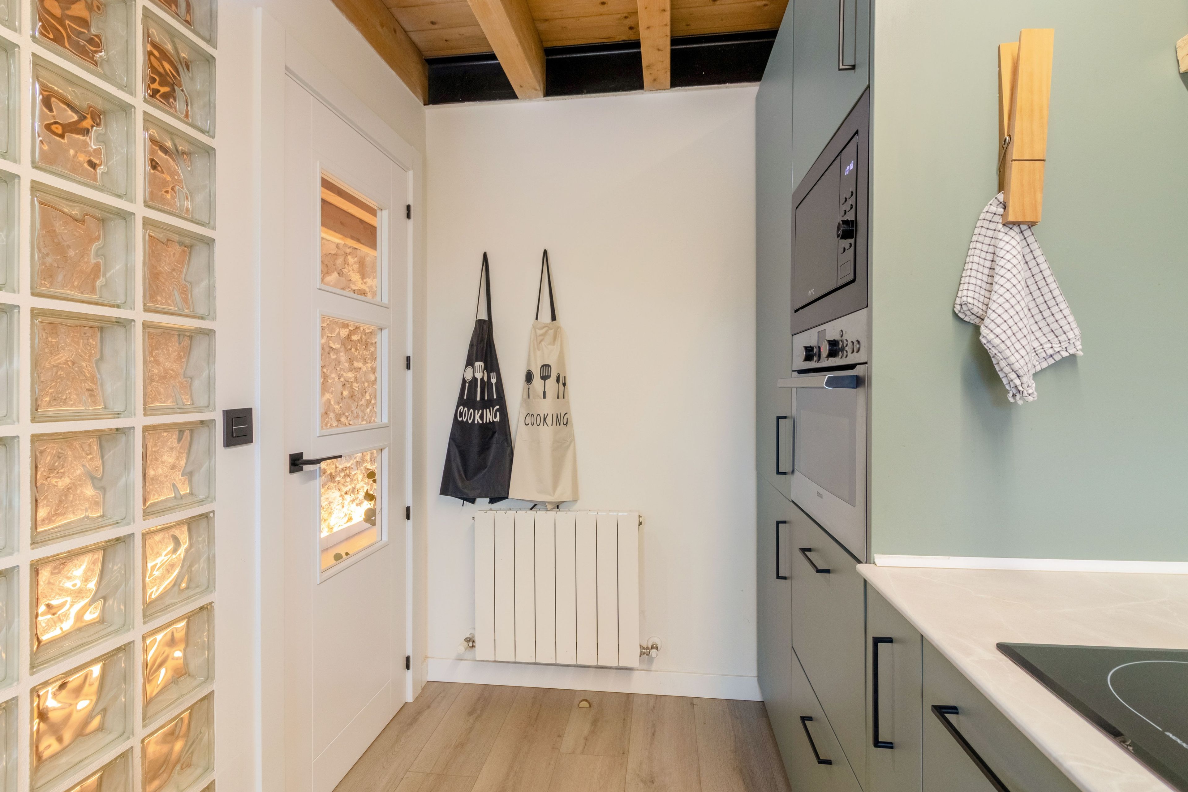 Una cocina con una puerta blanca, un radiador blanco y un techo de madera.