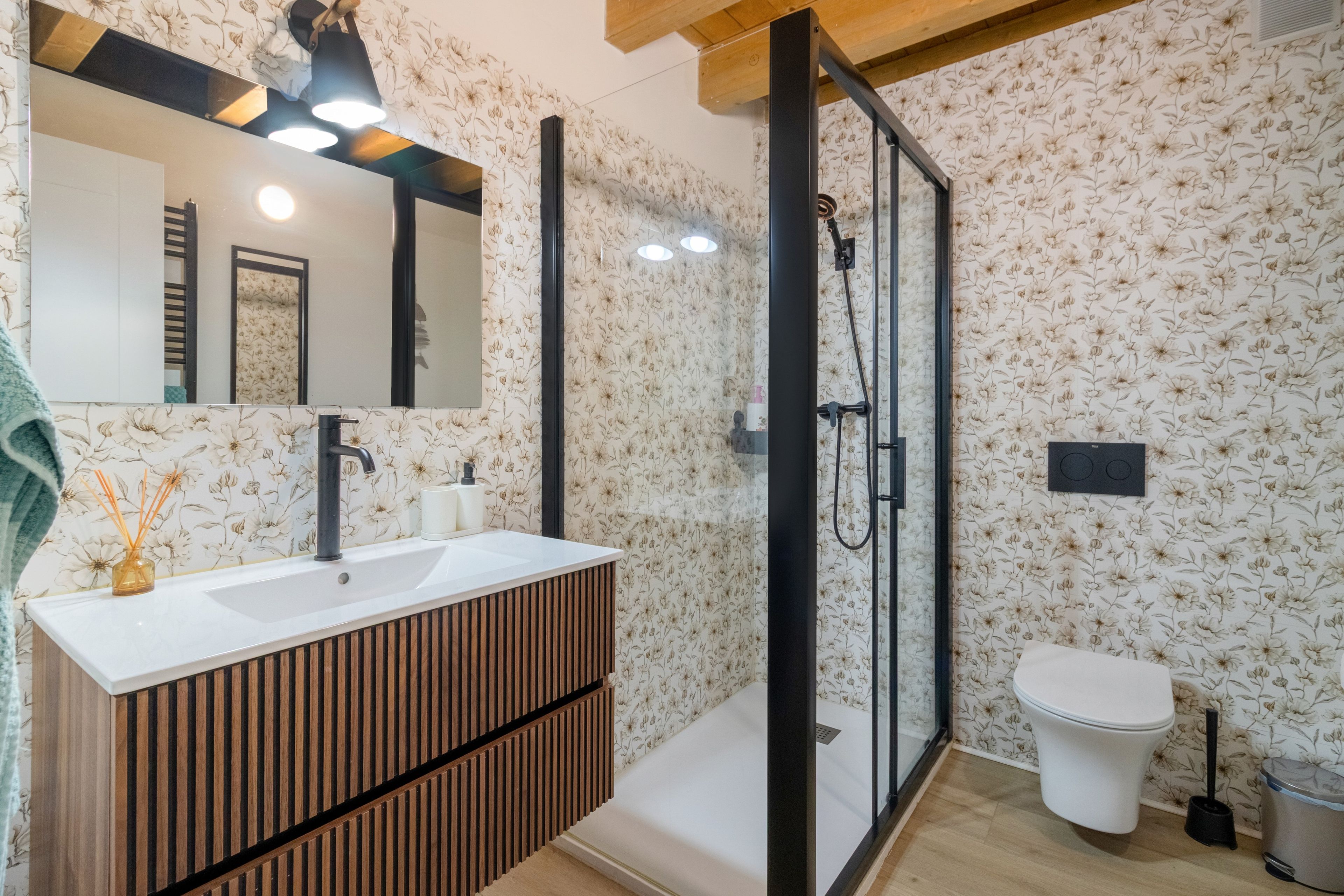 Un baño con tocador de madera, cabina de ducha con vidrio y un inodoro.