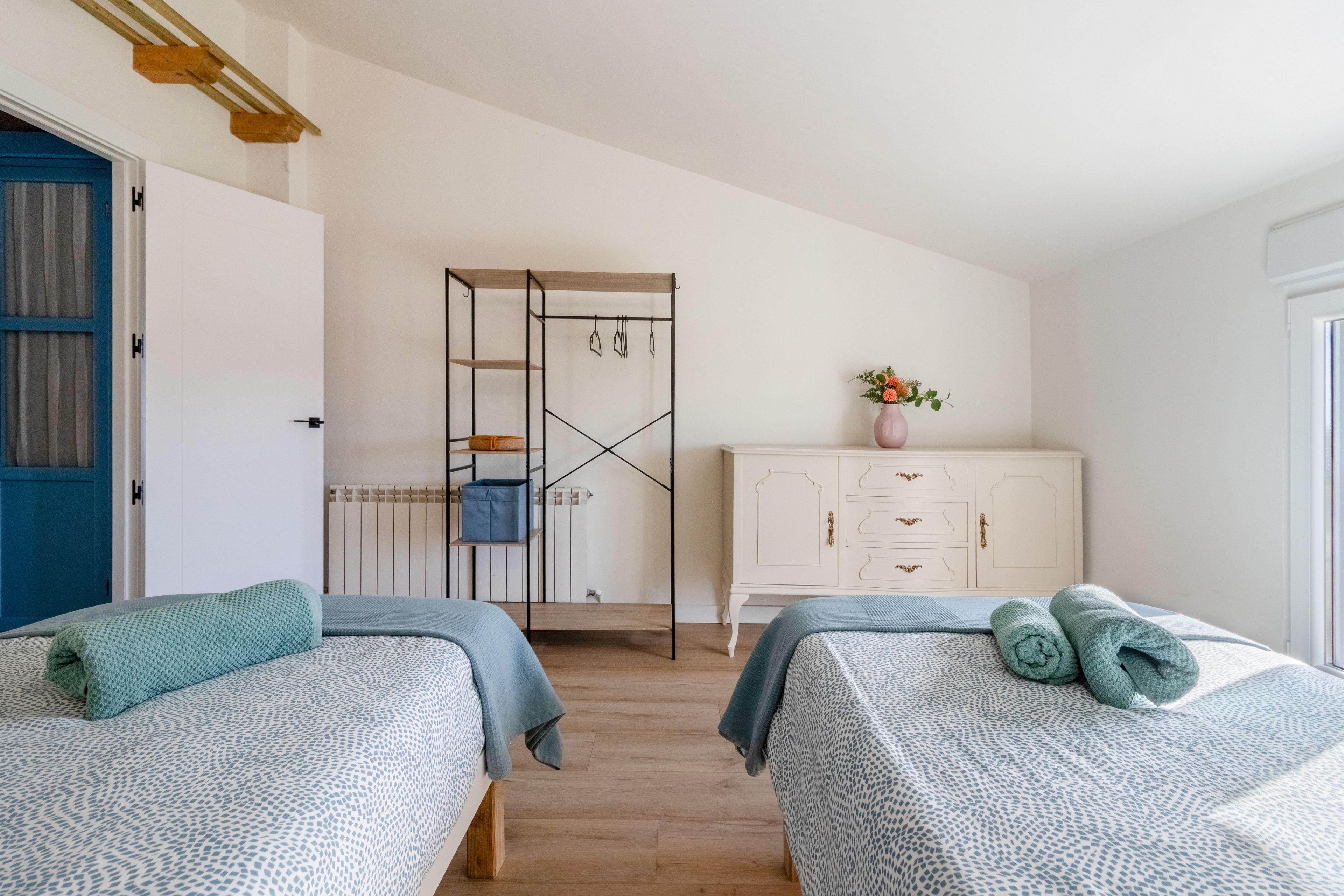 Een slaapkamer met twee bedden, een kledingkast, een radiator en een deur met een blauw frame.