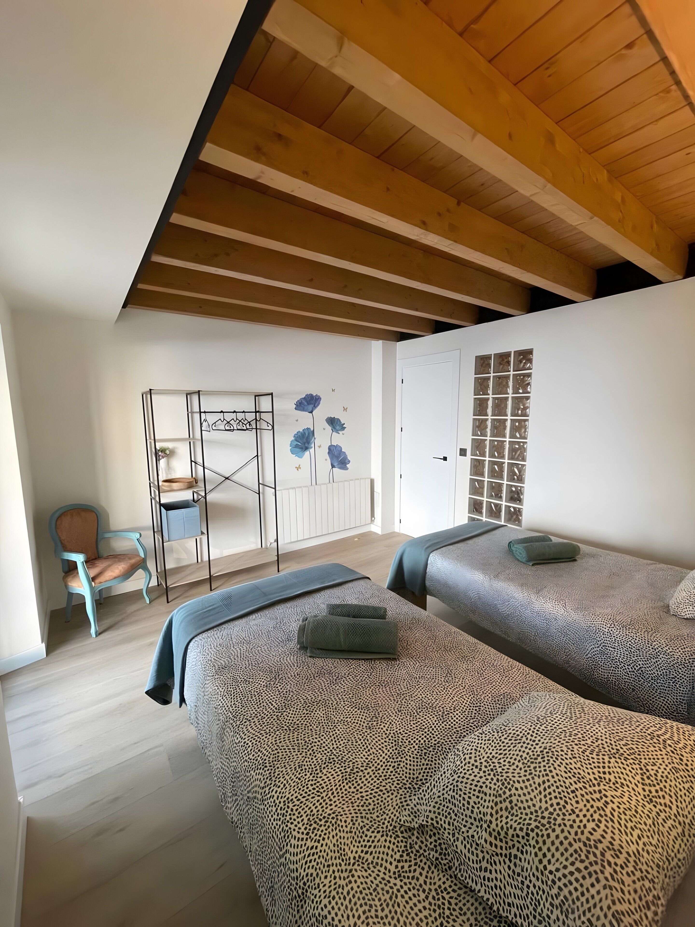 Un dormitorio con dos camas, una silla, un radiador y un armario.