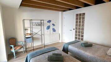 Un dormitorio con dos camas, una silla, un radiador y un armario.