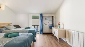 Un dormitorio con dos camas, un aparador, una ventana con cortinas y un balcón.