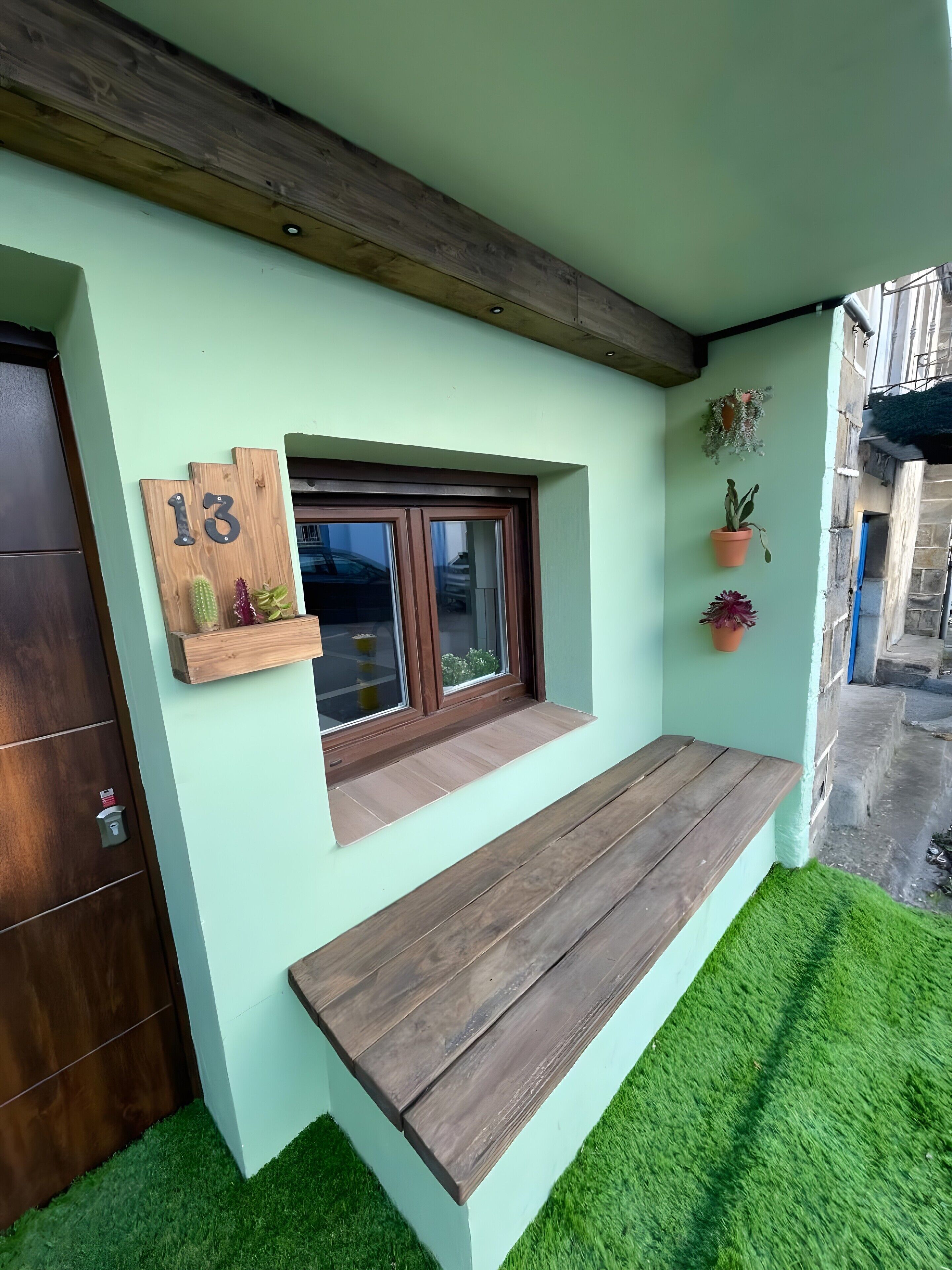 Fachada moderna con banco de madera, ventana con vistas y una puerta.