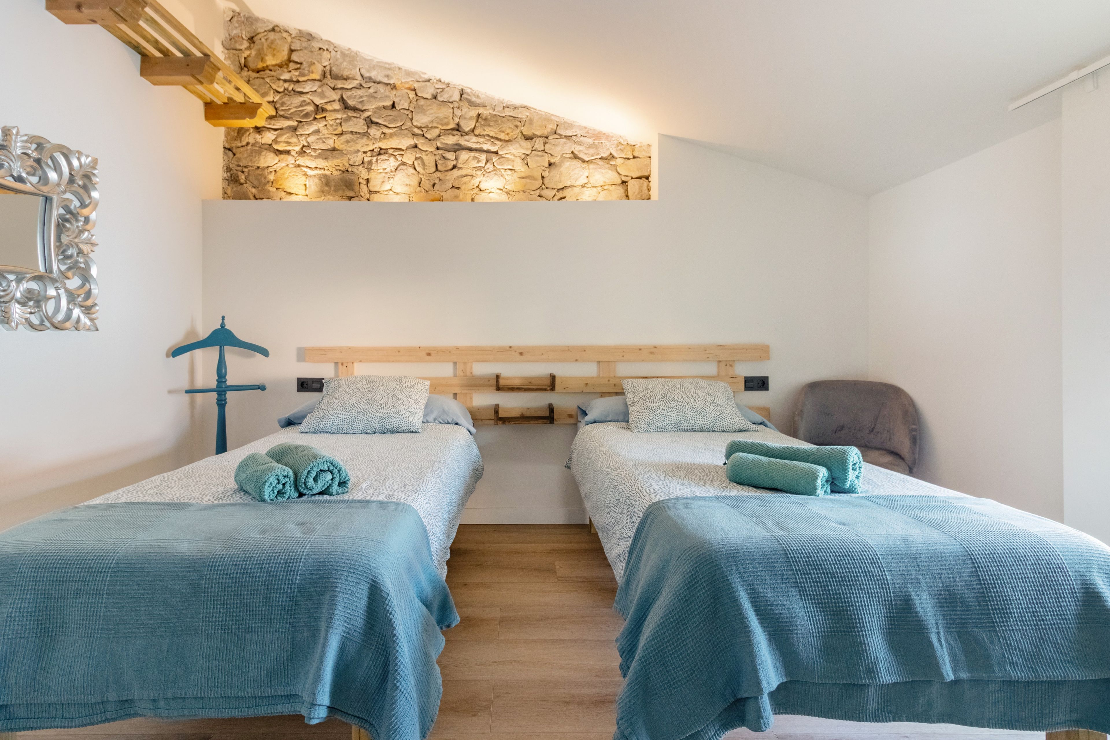 Une chambre avec deux lits, un mur en pierre et un plafond en bois.