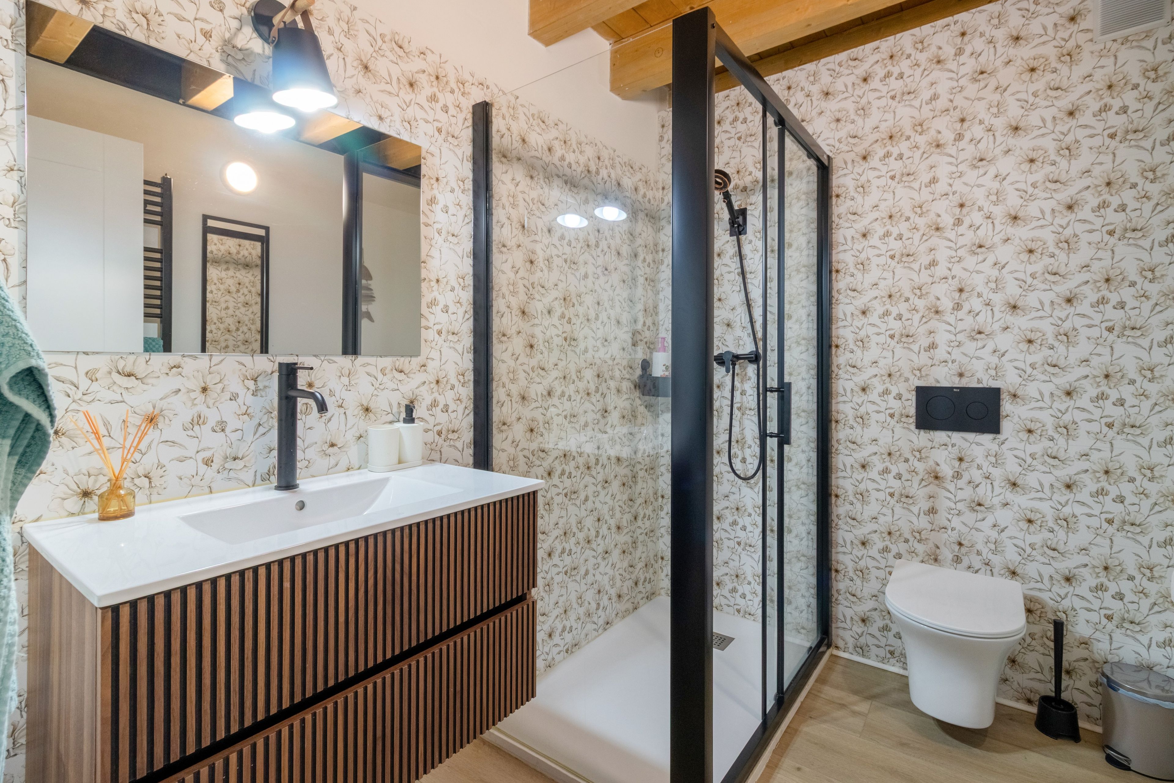 Un baño moderno con tocador de madera, cabina de ducha con mampara de vidrio y un inodoro.