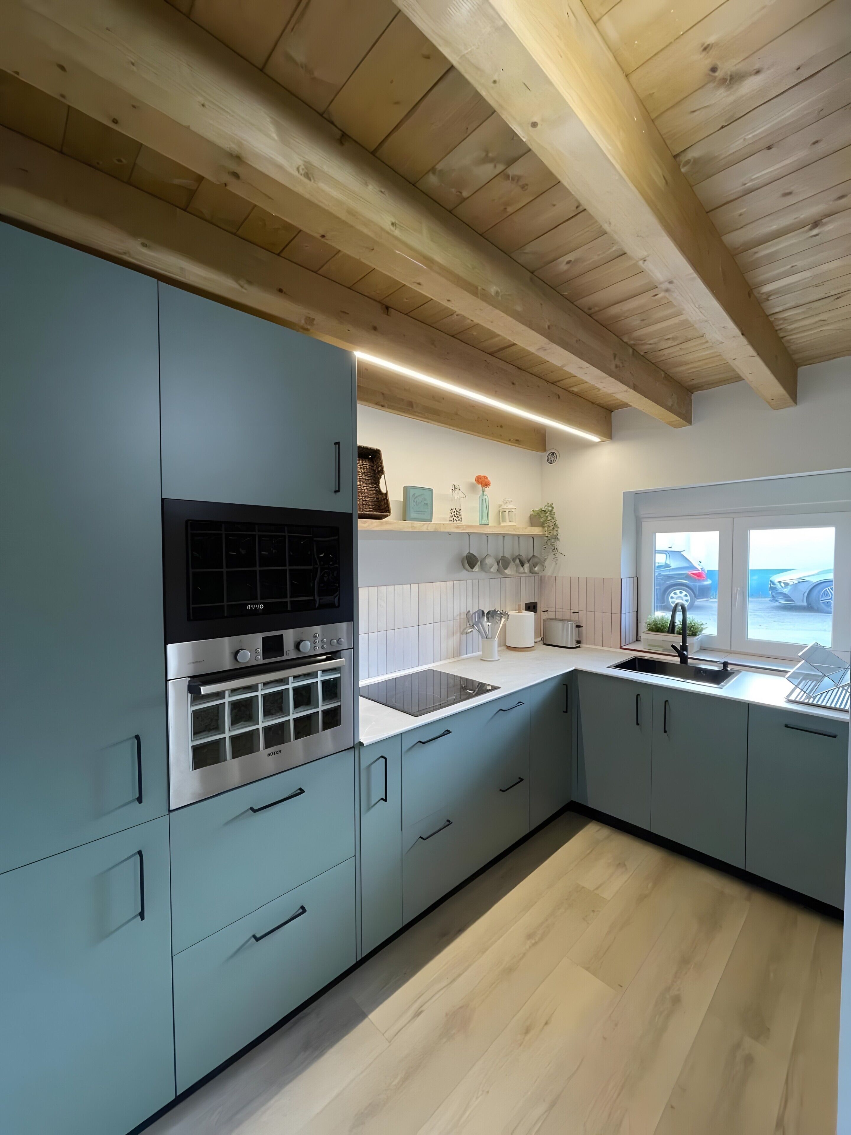 Una cocina moderna con armarios azul claro, electrodomésticos de acero inoxidable y techo de madera.