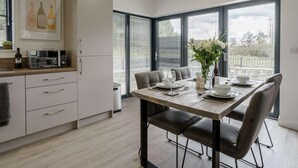 A modern kitchen with a dining area, large windows, and a view of the outdoors. - 2 Bed in Usk- (oc-82391) (Kemeys Commander)