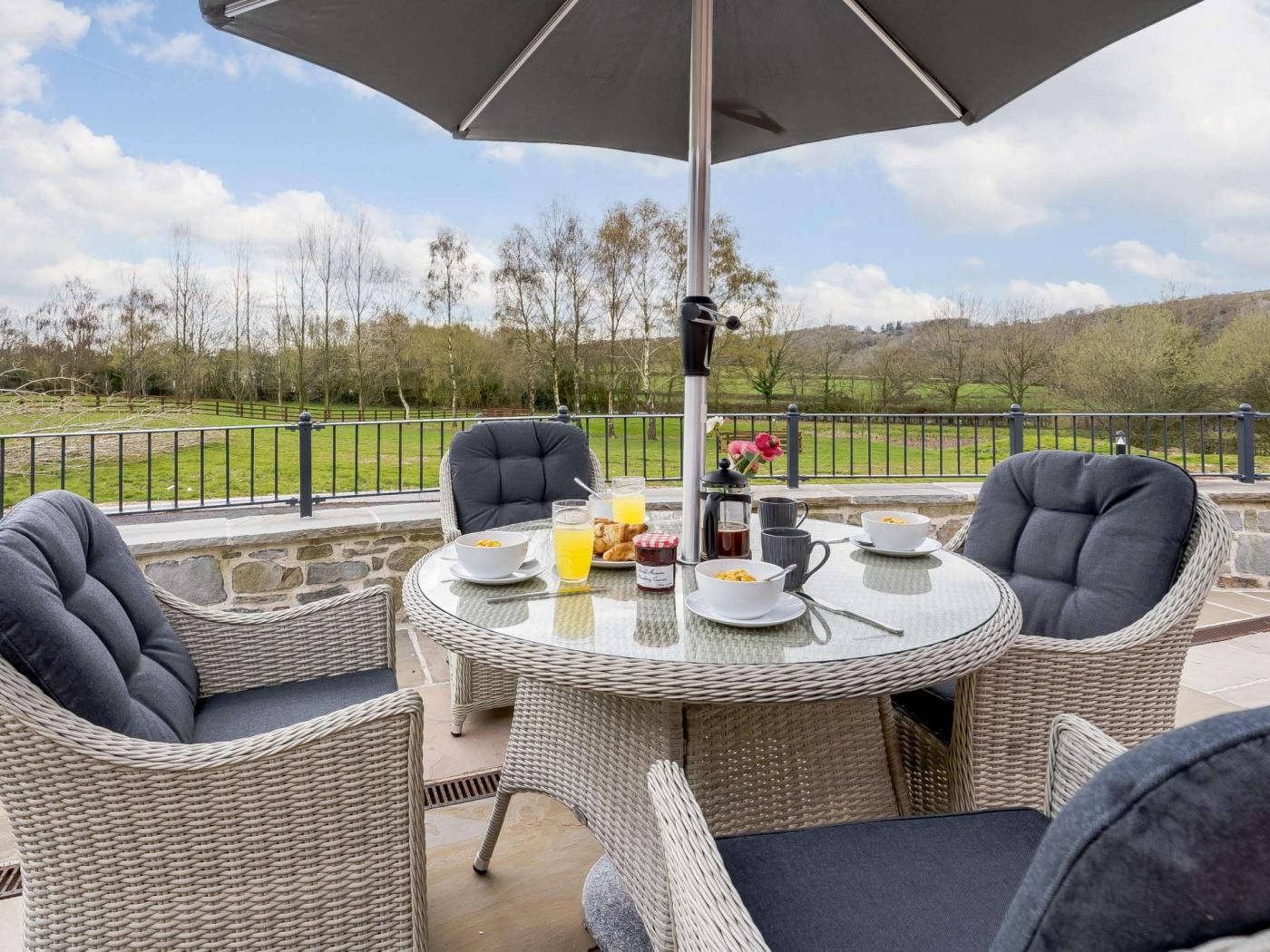 An outdoor dining area with wicker chairs and a table set for breakfast.