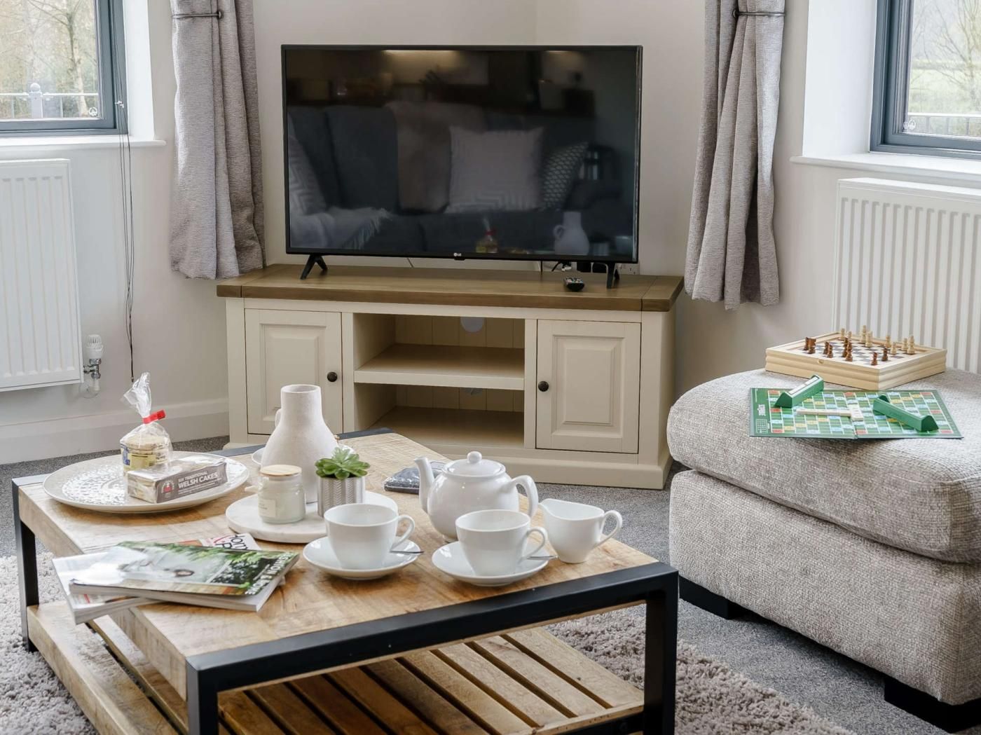 Un salon avec un téléviseur, une table basse avec des tasses et un jeu de société, et un canapé.