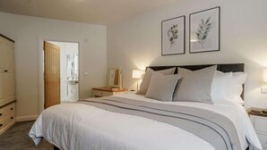 A bedroom with a bed, bedside tables, a dresser, and two framed botanical prints on the wall. - 2 Bed in Usk- (oc-82391) (Kemeys Commander)