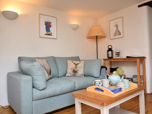 Ein Wohnzimmer mit einer Couch, einem Holztisch, Wandlampen und gerahmten Kunstwerken.