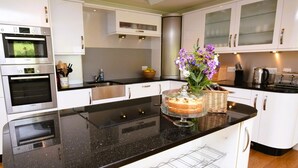 Une cuisine moderne avec des meubles blancs, un plan de travail noir et un four Bosch.
