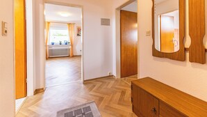 Ein Flur mit Holzboden, einem Holzschrank und einem Spiegel an der Wand.