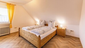 Ein Schlafzimmer mit einem hölzernen Bett, einem Nachttisch, einer Lampe und einem Fenster mit Vorhängen.