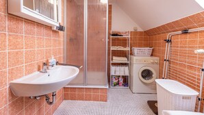Ein Badezimmer mit Waschbecken, Dusche und Waschmaschine.