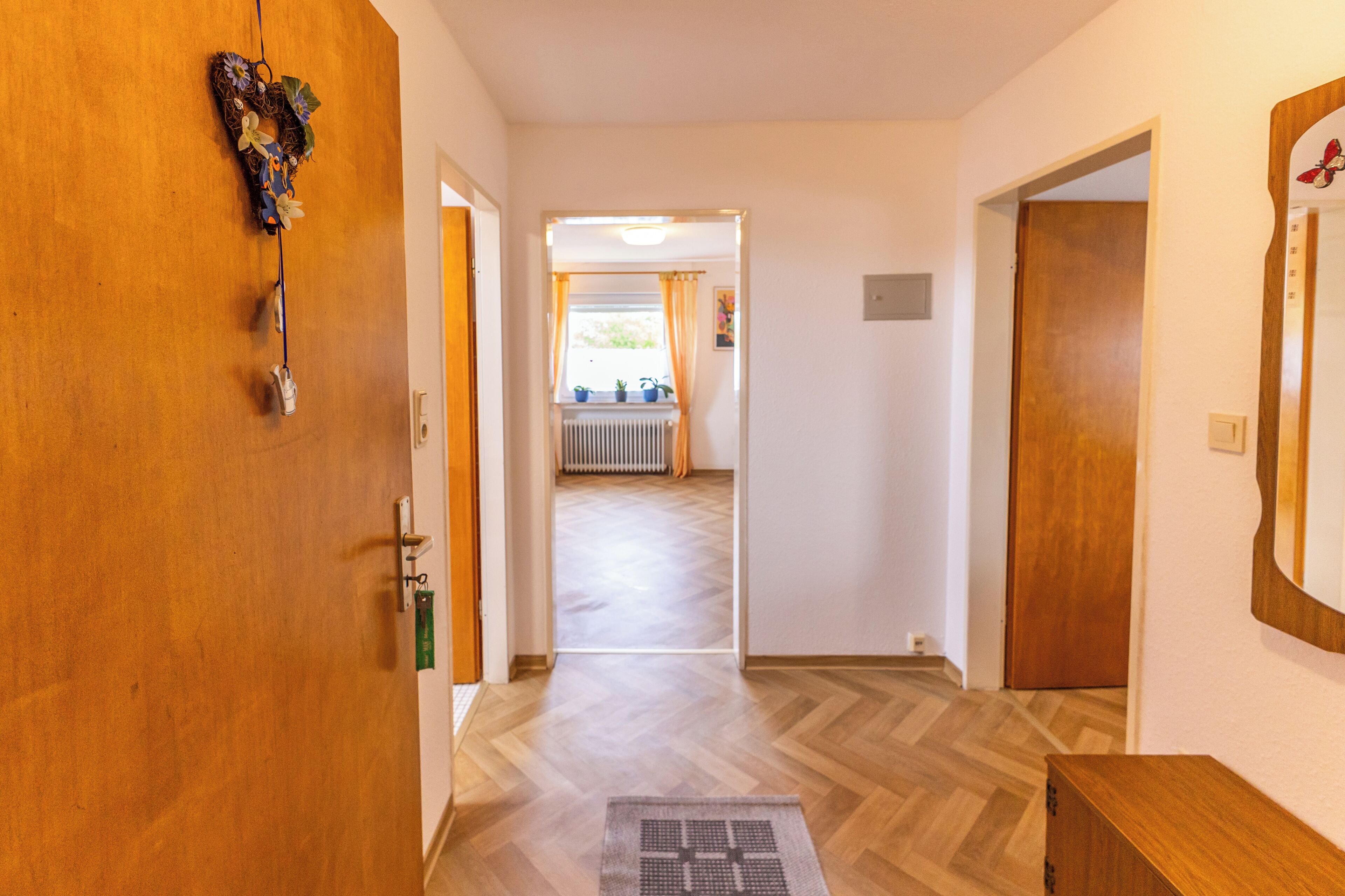 A hallway with wooden doors, a radiator, and a window with curtains.
