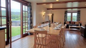 A dining area with a large table set for a meal, a sofa, and a view of the outdoors. - 6 Bed in Llandovery (oc-82441) (Llanfair-ar-y-Bryn)