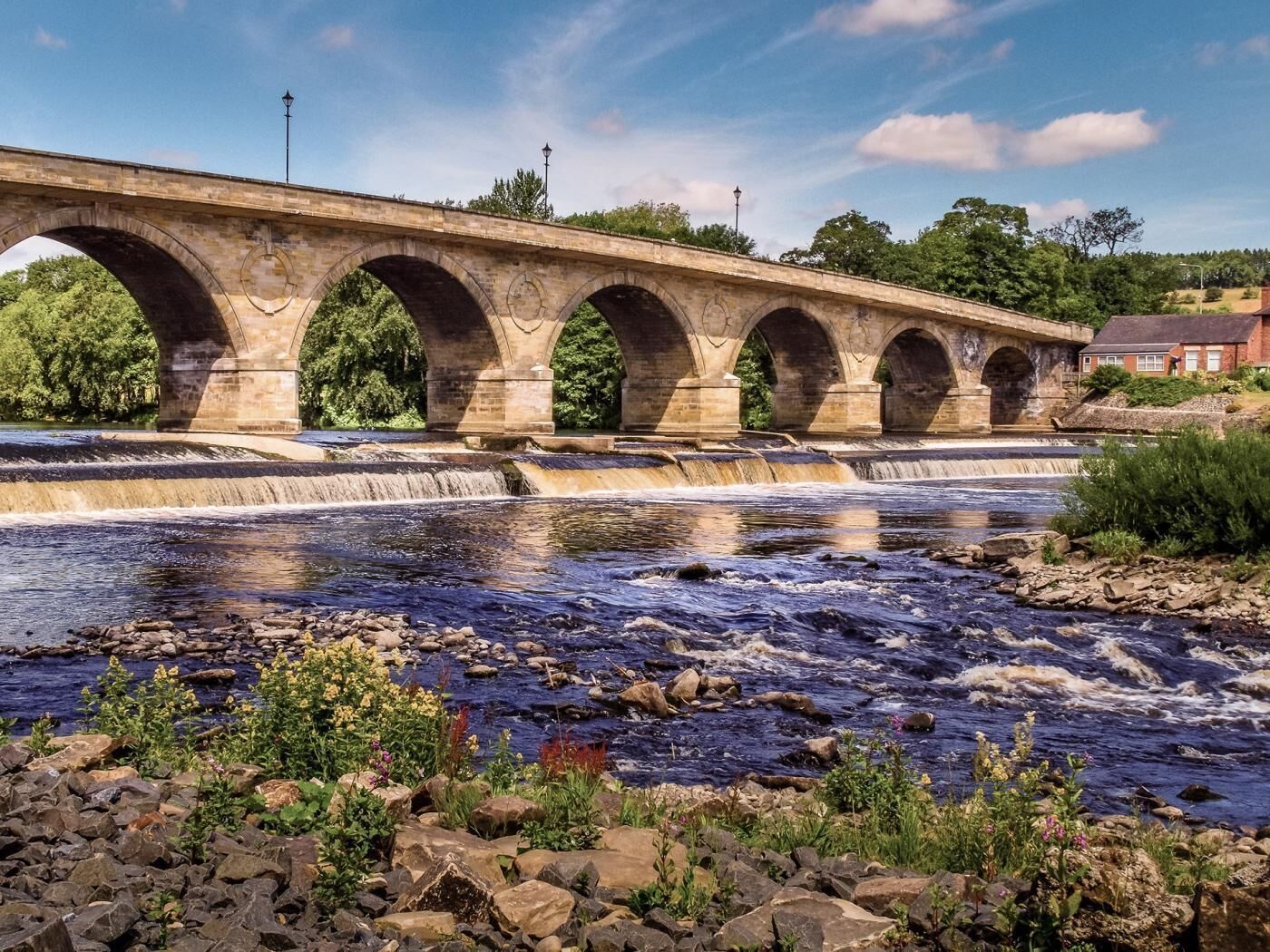 Een stenen brug met meerdere bogen over een rivier.