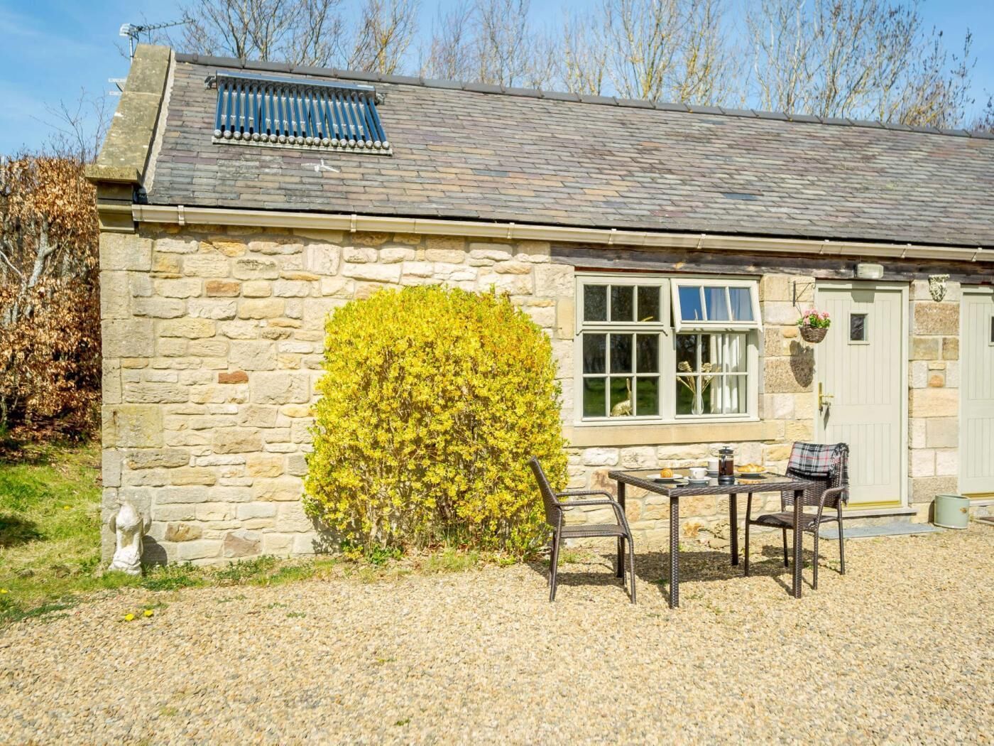 Une petite maison en pierre avec un patio, une fenêtre donnant sur un beau paysage et une porte.