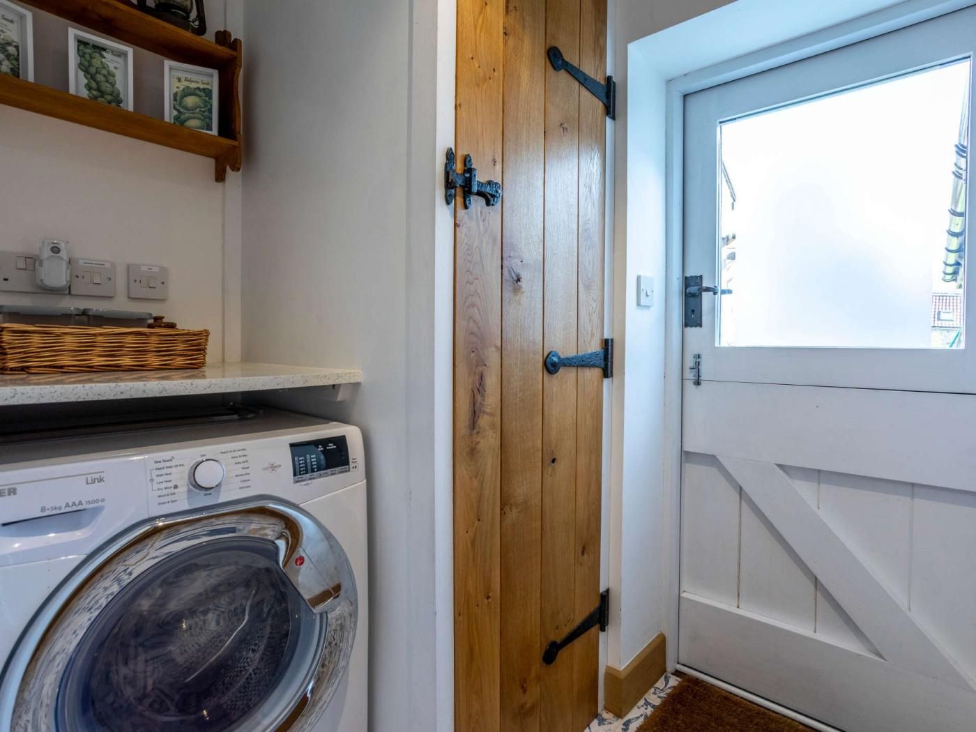 A laundry area with a washing machine, wooden door, and a window with a view.