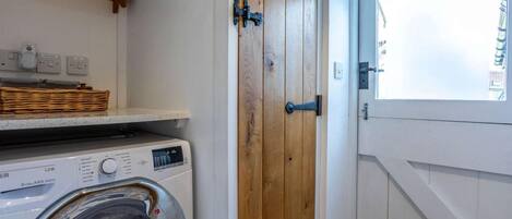 A laundry area with a washing machine, wooden door, and a window with a view.