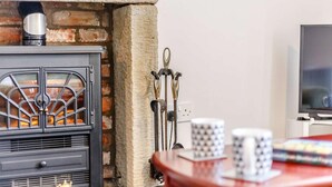 A room with a fireplace, a television, and a table with mugs. - 2 Bed in Berwick-upon-tweed (oc-81273) (Berwick-upon-Tweed)