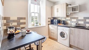 A modern kitchen with a built-in washing machine, a coffee maker, and a window with a view. - 2 Bed in Berwick-upon-tweed (oc-81273) (Berwick-upon-Tweed)