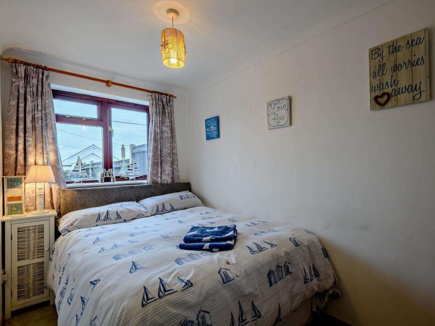 Ein Schlafzimmer mit einem Bett, einem Fenster mit Vorhängen, einer Lampe und Wanddekorationen.