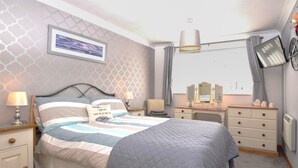 Ein Schlafzimmer mit einem Bett, Nachttischen, einem Schminktisch, einem Spiegel und einem Fenster mit Vorhängen.