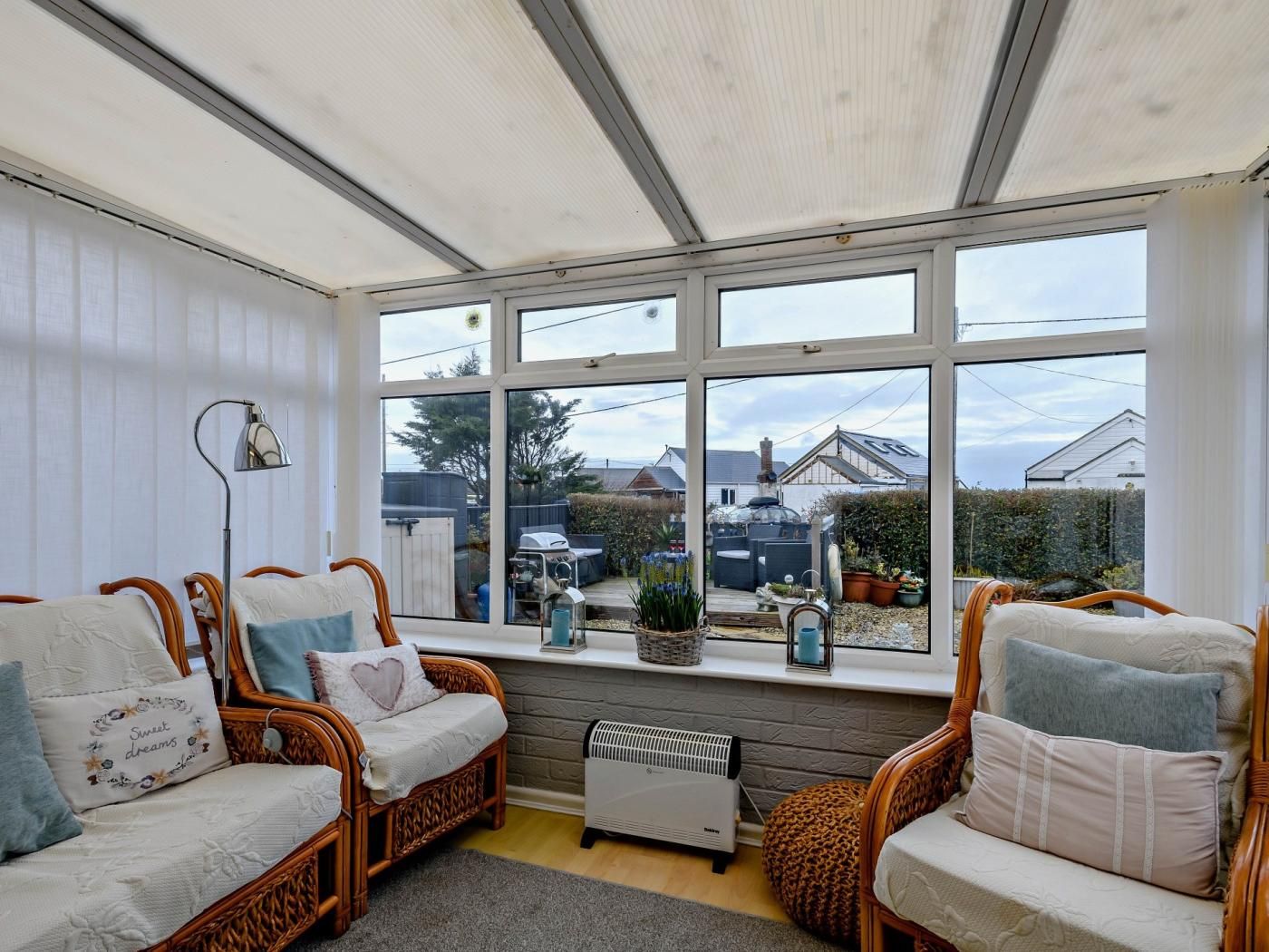 A conservatory with wicker furniture, a radiator, and a view of the outside.
