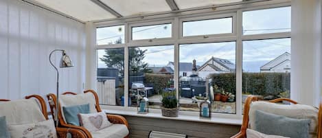 A conservatory with wicker furniture, a radiator, and a view of the outside.