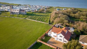 A coastal residential area with a large white house, a church, and a sea view. - 4 Bed in Cromer (oc-81469) (West Runton)