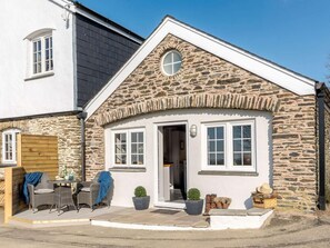 A stone house with a white exterior, a small porch with wicker furniture, and a circular window above the entrance. - 1 Bed in Challacombe (oc-81477) (Challacombe)