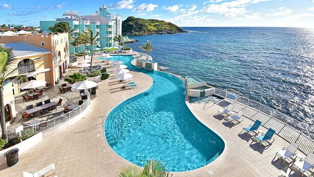 Un complex turístic amb piscina, gandules i vistes a l'oceà.