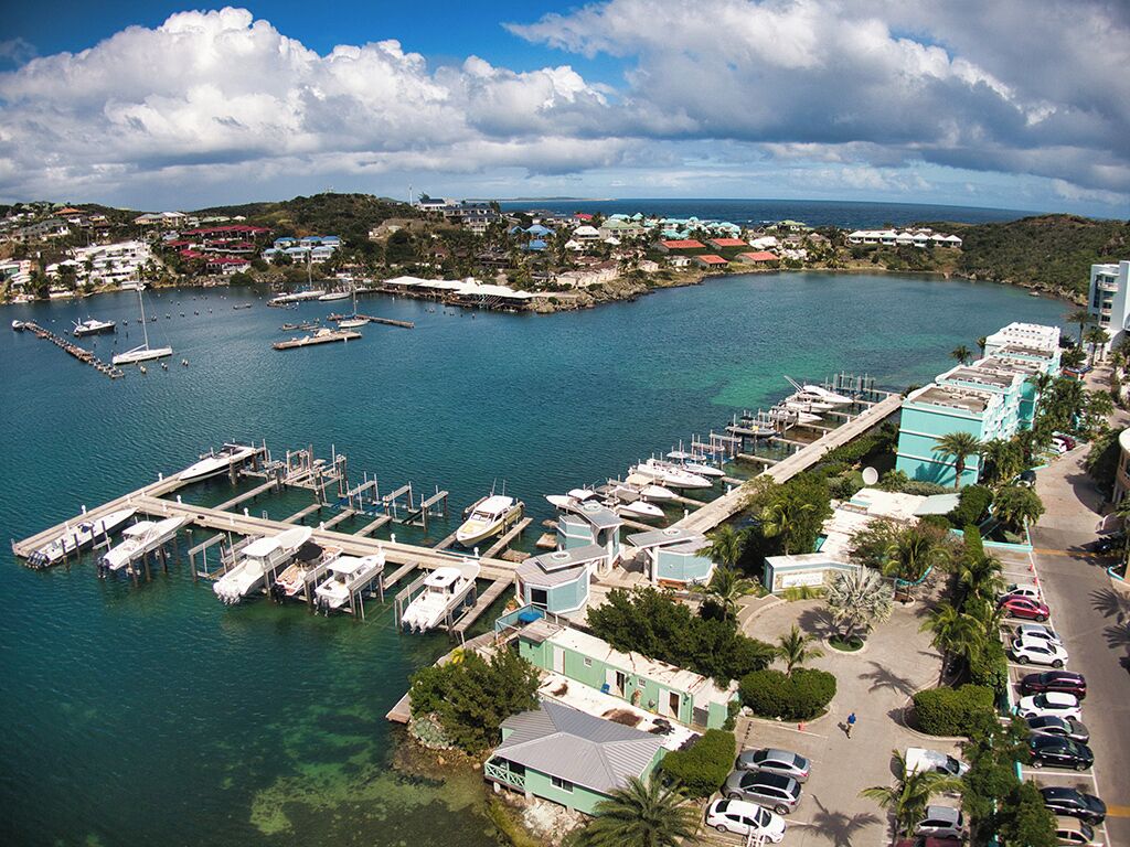 A marina with boats docked, a pier, and buildings with a view of the water.
