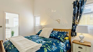 Een slaapkamer met een bed, nachtkastje, lamp en een muur met cirkelvormige patronen.