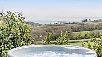 A hot tub with a view of the sea and hills.