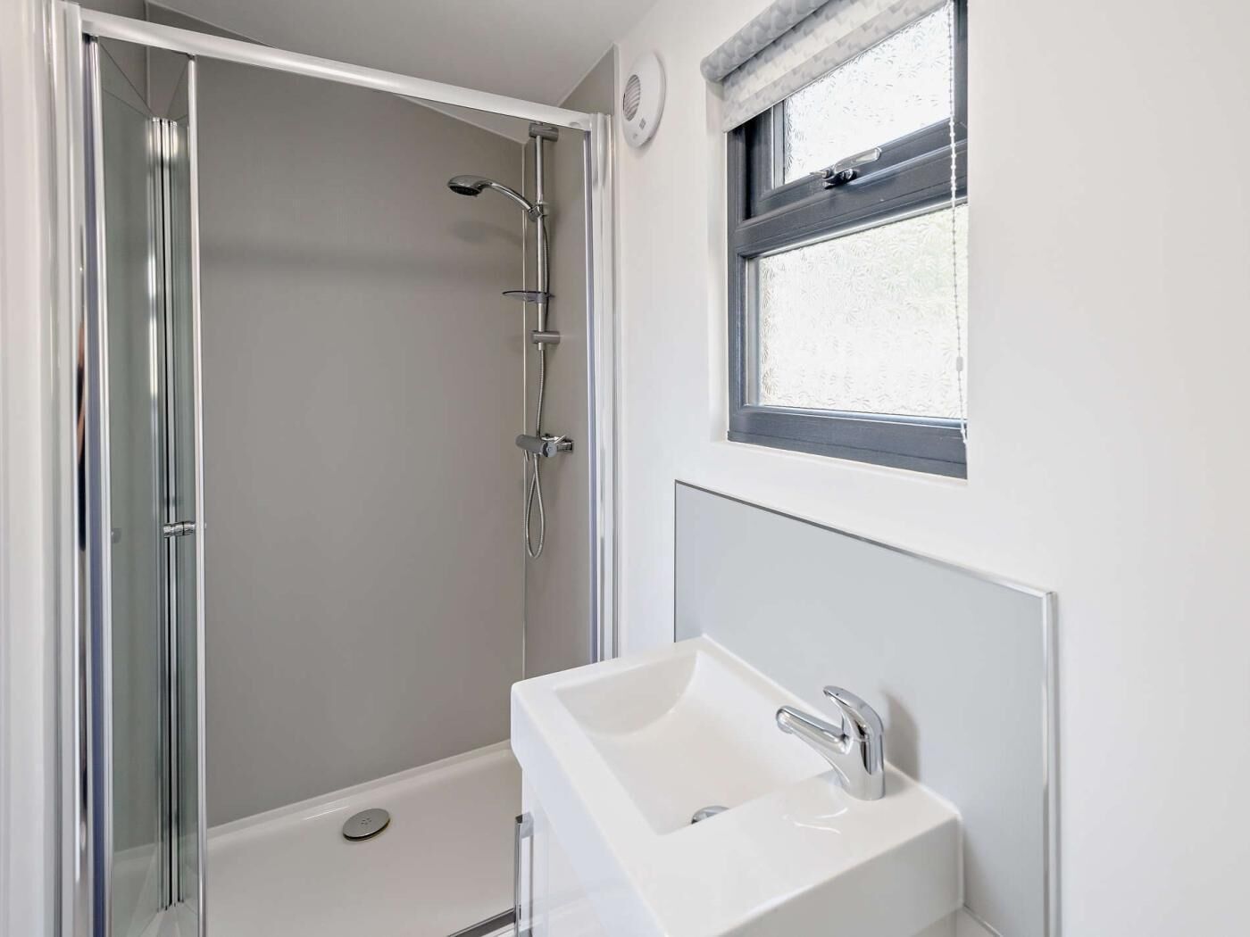 A bathroom with a shower, a sink, and a window.