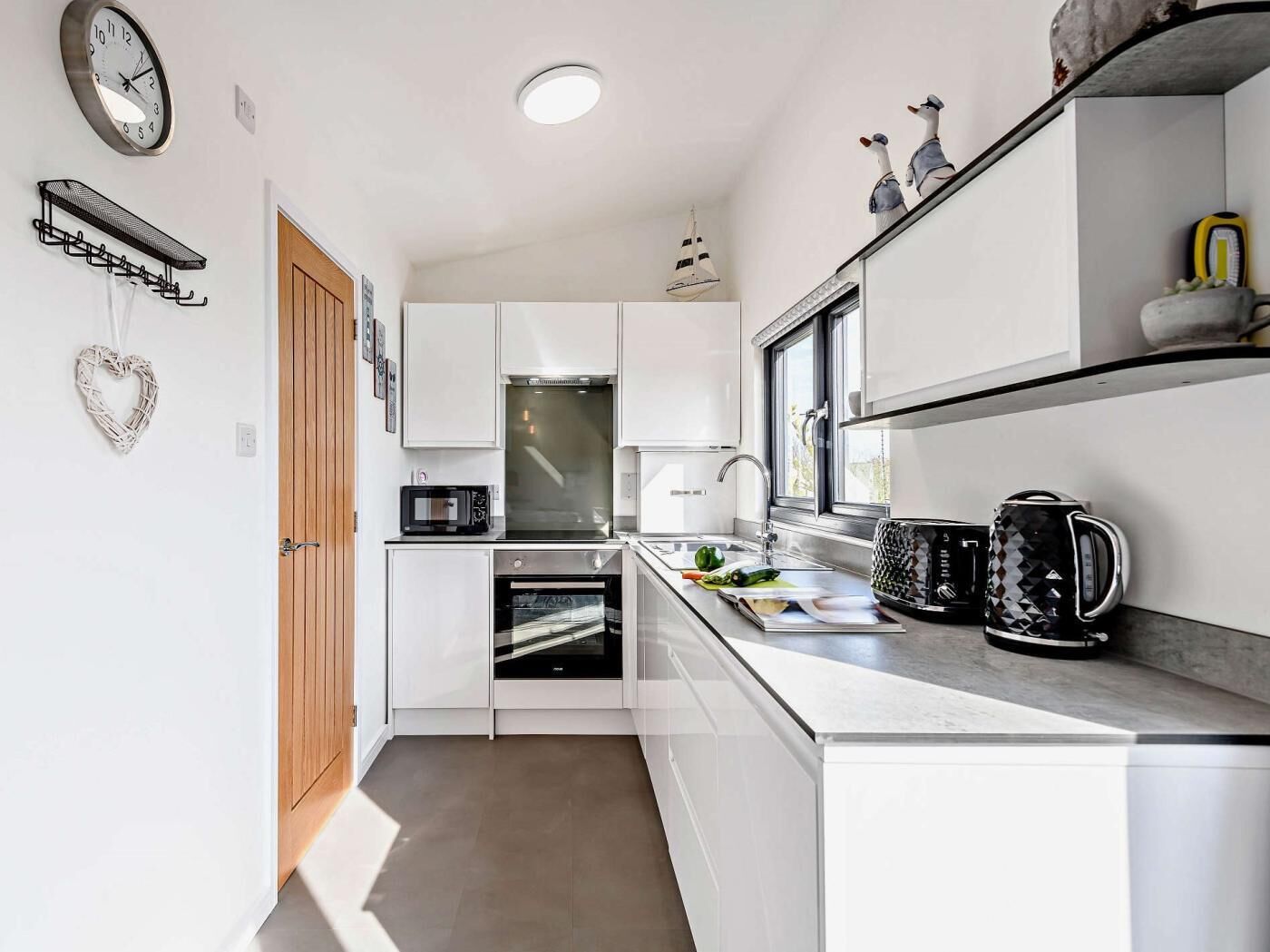 A modern kitchen with white cabinetry, a microwave, oven, and a coffee maker.