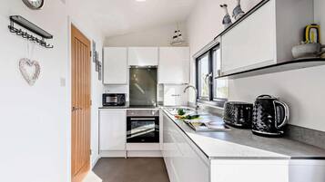 A modern kitchen with white cabinetry, a microwave, oven, and a coffee maker.