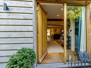 A wooden exterior with a sliding glass door leading to an interior with a sofa, lamp, and a view of the outdoors. - 2 Bed in Hereford (oc-82095) (Lulham)