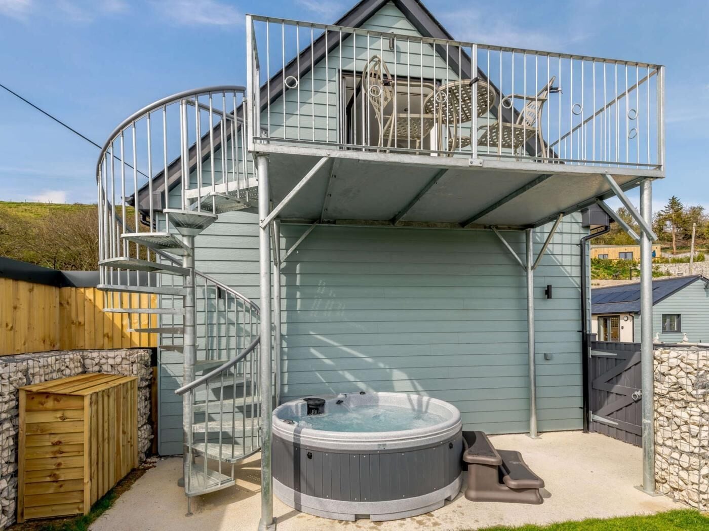 Un bâtiment à deux étages doté d’un escalier en colimaçon, d’un jacuzzi et d’un patio couvert.