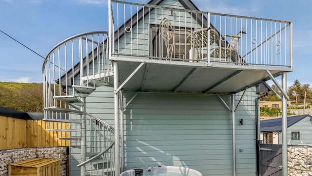 Un edificio a due piani con una scala a chiocciola, una vasca idromassaggio e un patio coperto.
