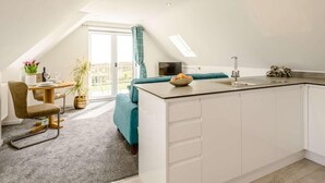 Una cucina moderna con un'isola centrale, un'area pranzo con tavolo e sedie, e un angolo salotto accogliente con un divano.