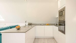 Una cucina moderna con mobili bianchi, un piano di lavoro in granito ed elettrodomestici in acciaio inossidabile.