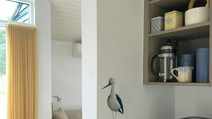 Une cuisine moderne équipée d’une machine à café, d’étagères avec des récipients et d’une décoration murale représentant un oiseau.