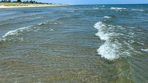Une plage à l’eau claire, avec une côte qui s’étend au loin.